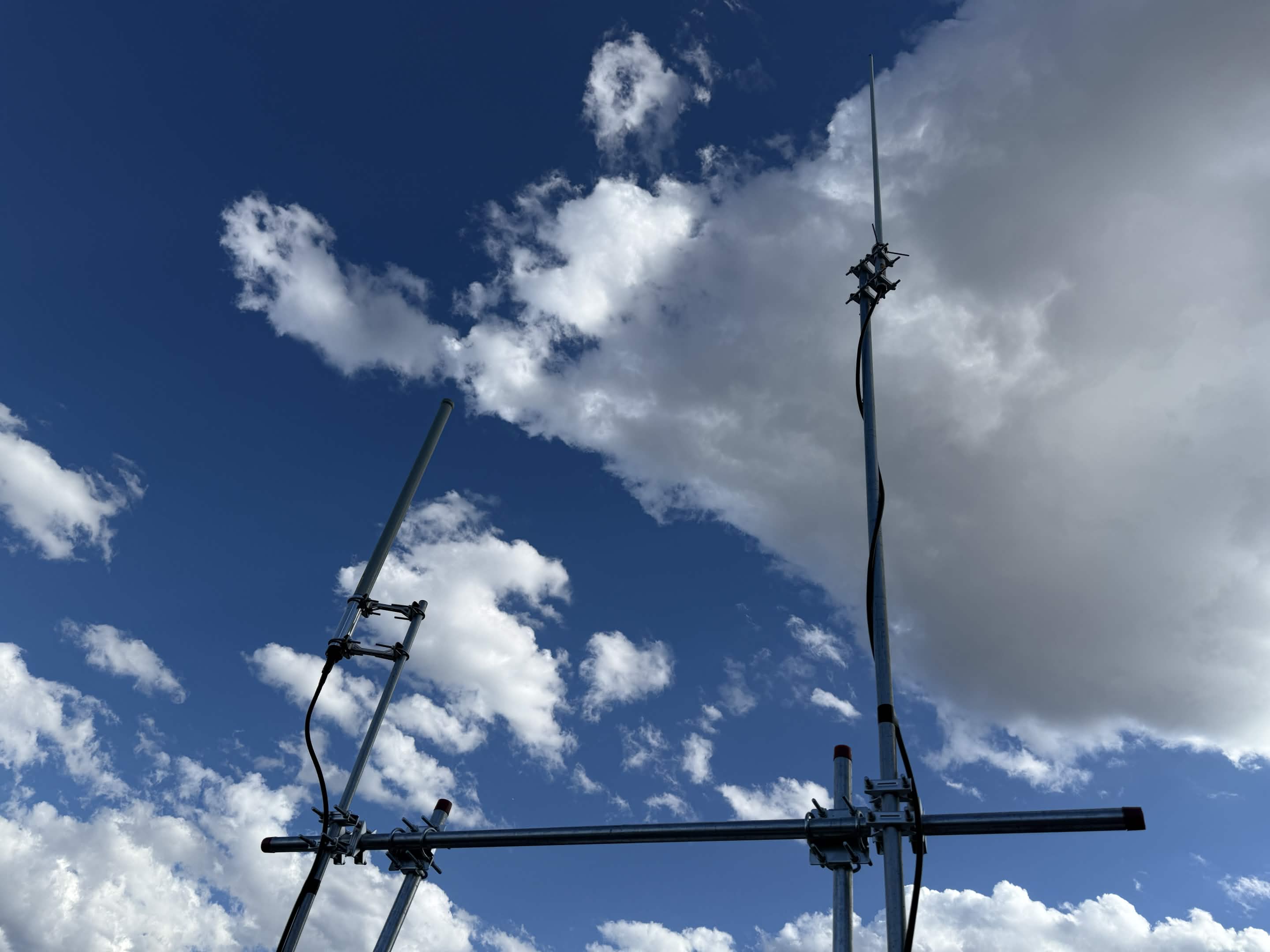 Two antennas on an H-shaped pipe structure in front of a blue sky.